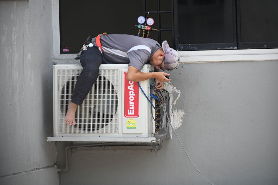 HVAC technician working on an outdoor air conditioning unit